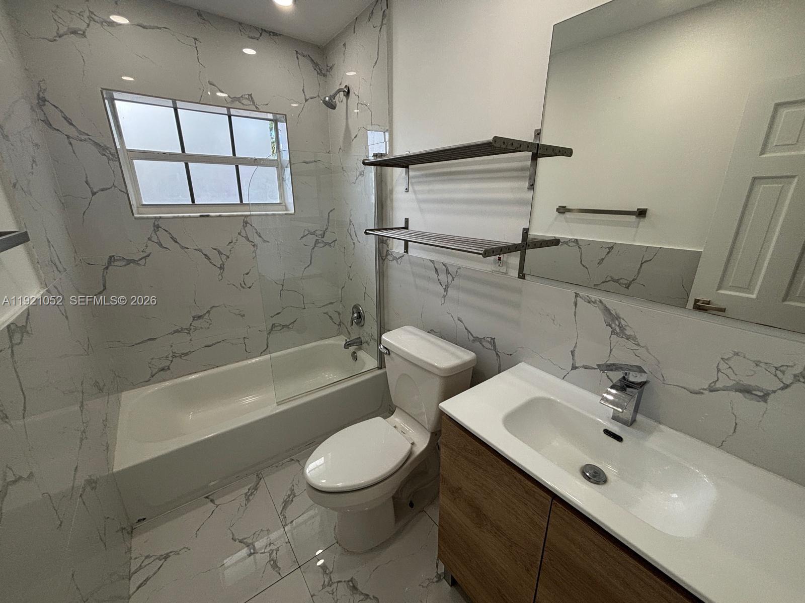 725 91st Street Surfside, FL 33154 - Photo 17 of 32 a bathroom with a bathtub shower sink vanity mirror and toilet