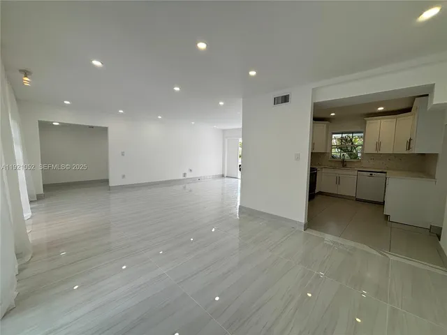 a view of a kitchen with kitchen island a sink wooden floor and a refrigerator