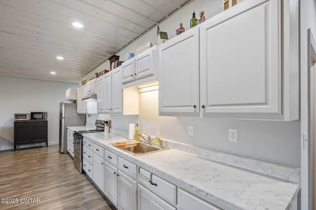 a living room with furniture a flat screen tv and a refrigerator