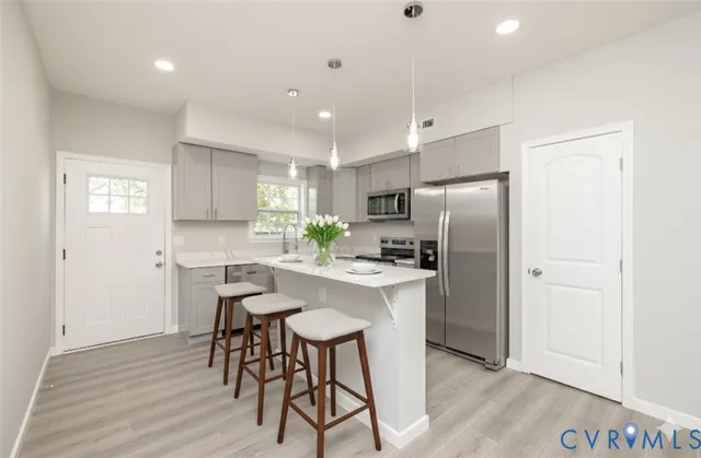 a kitchen with stainless steel appliances a refrigerator a stove a sink dishwasher and a refrigerator with wooden floor