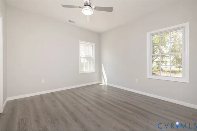 an empty room with wooden floor and windows