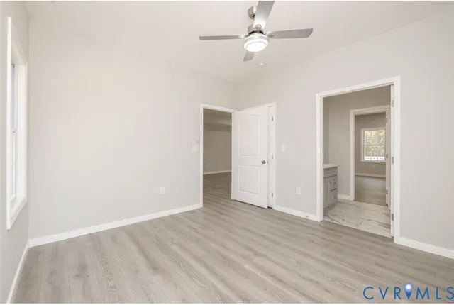 an empty room with wooden floor and ceiling fan