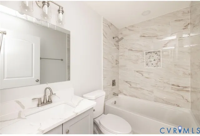 a bathroom with a granite countertop bathtub shower sink vanity mirror and toilet