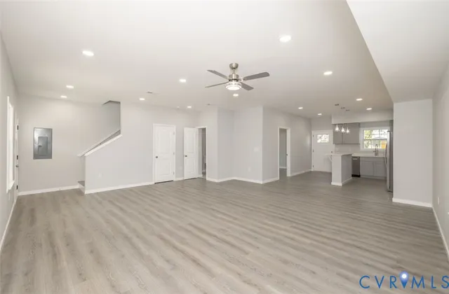 a view of an empty room with wooden floor and a ceiling fan