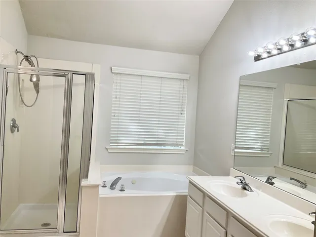 a bathroom with a tub sink shower and mirror