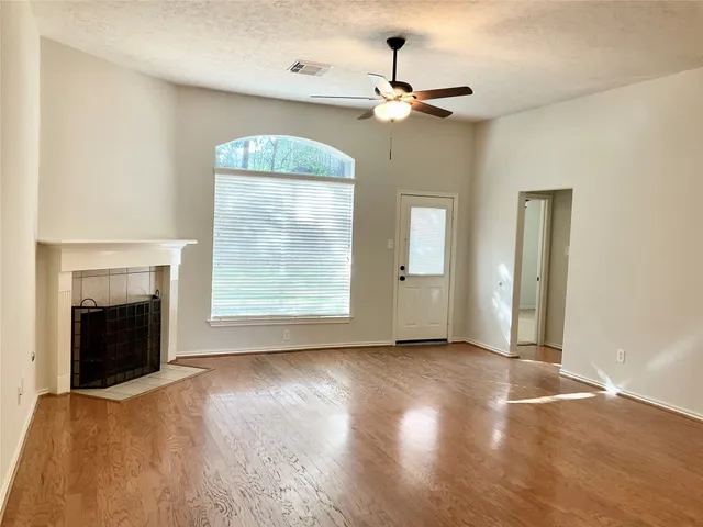 a view of an empty room with wooden floor fireplace and a window
