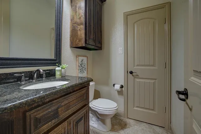 a bathroom with a granite countertop toilet sink and mirror