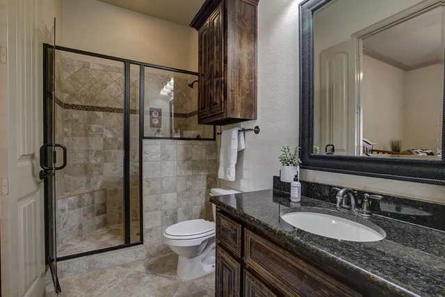 a bathroom with a granite countertop sink toilet a mirror and shower
