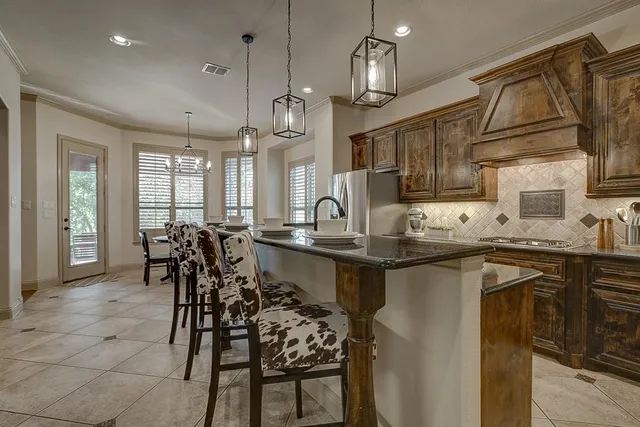a kitchen with stainless steel appliances granite countertop table chairs sink and cabinets