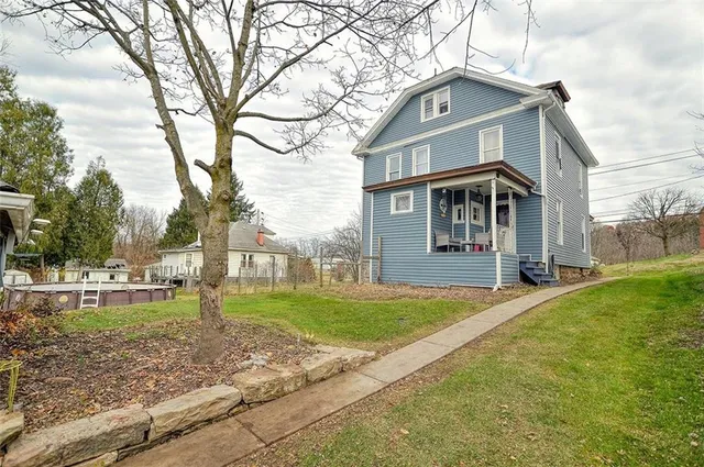 a front view of a house with garden and trees