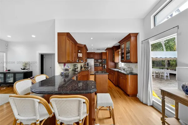 a kitchen with stainless steel appliances granite countertop a stove a refrigerator a kitchen island with chairs and wooden floor