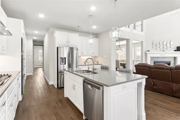 a kitchen with stainless steel appliances kitchen island granite countertop a table chairs and a refrigerator