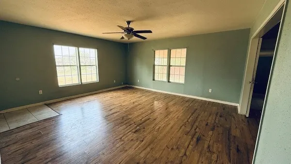 a view of empty room with wooden floor and fan