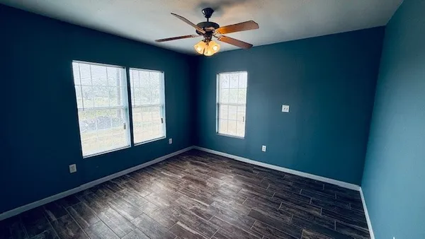 a view of empty room with wooden floor and fan
