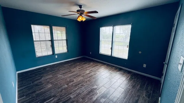 an empty room with windows and ceiling fan