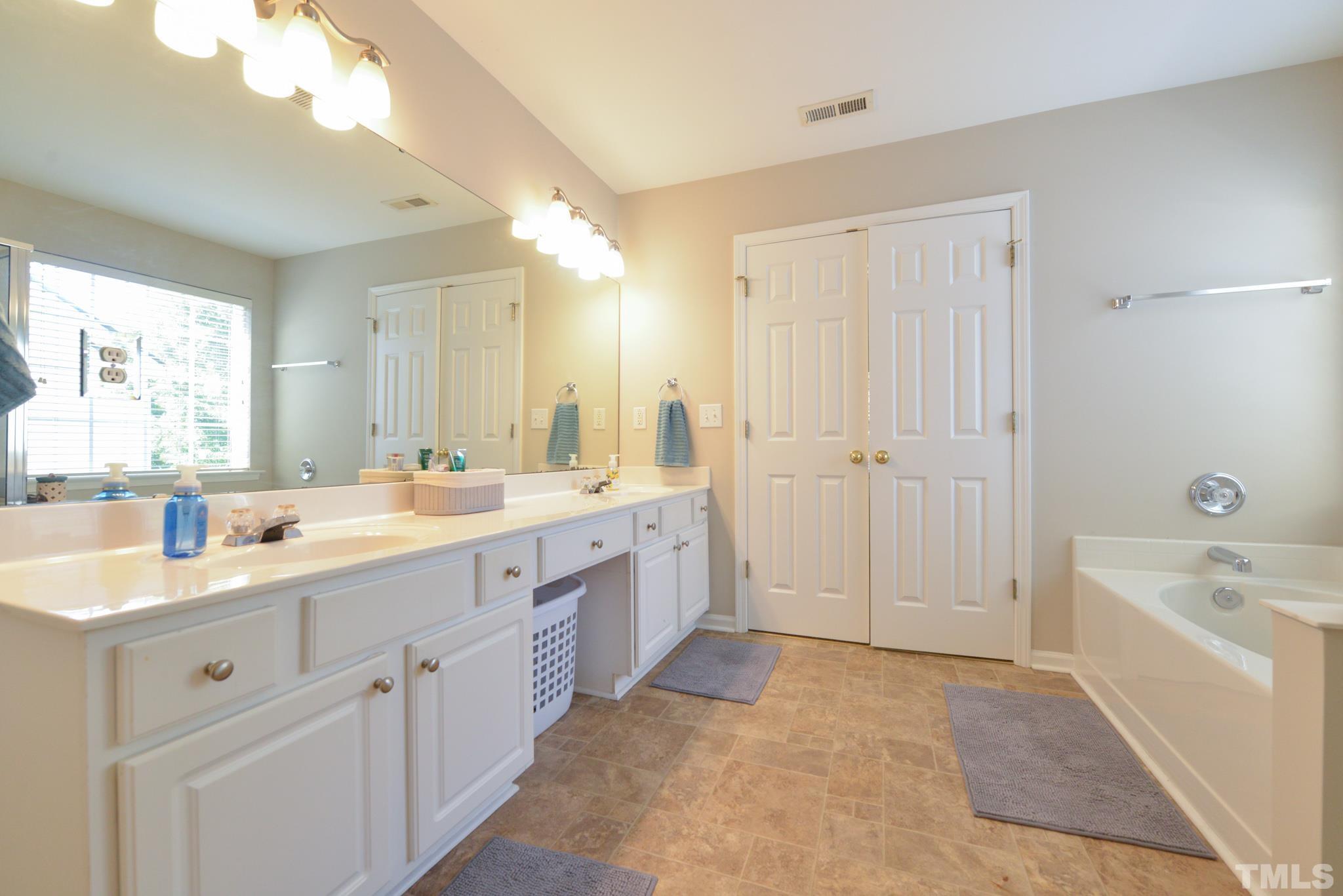 1513 Nealstone Way Raleigh, NC 27614 - Photo 21 of 30 a spacious bathroom with a double vanity sink a mirror and a bathtub