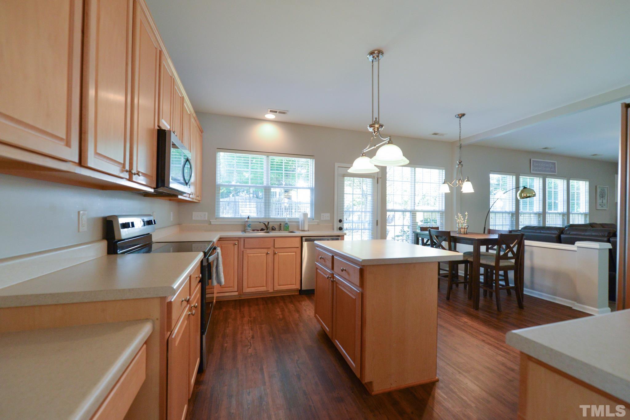 1513 Nealstone Way Raleigh, NC 27614 - Photo 8 of 30 a kitchen with kitchen island granite countertop a stove a sink a dining table and chairs with wooden floor
