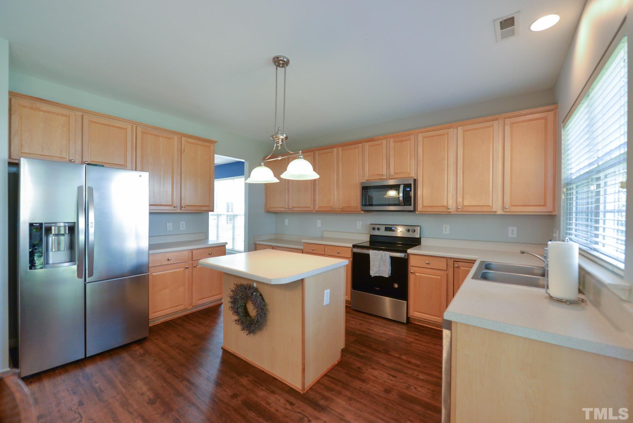 1513 Nealstone Way Raleigh, NC 27614 - Photo 9 of 30 a kitchen with stainless steel appliances granite countertop a sink a stove a refrigerator cabinets wooden floor and a window
