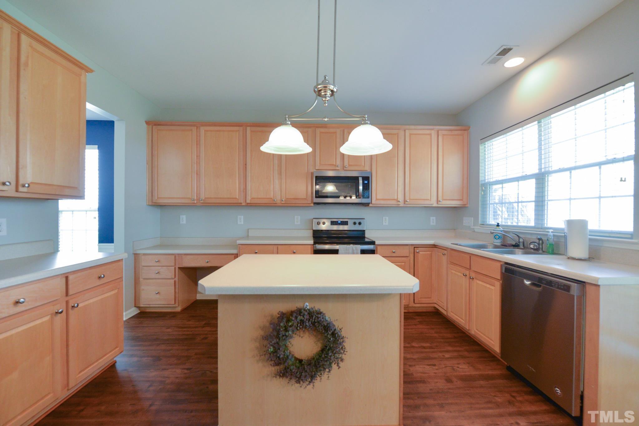 1513 Nealstone Way Raleigh, NC 27614 - Photo 10 of 30 a kitchen with stainless steel appliances a sink dishwasher stove and white cabinets with wooden floor