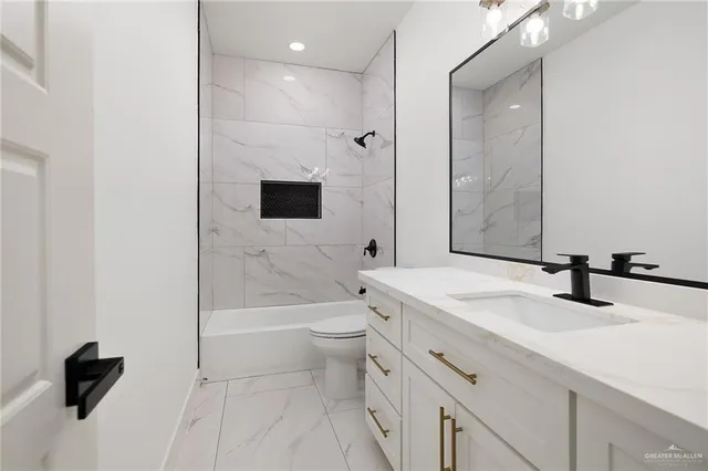 a bathroom with a granite countertop sink a toilet and a large mirror