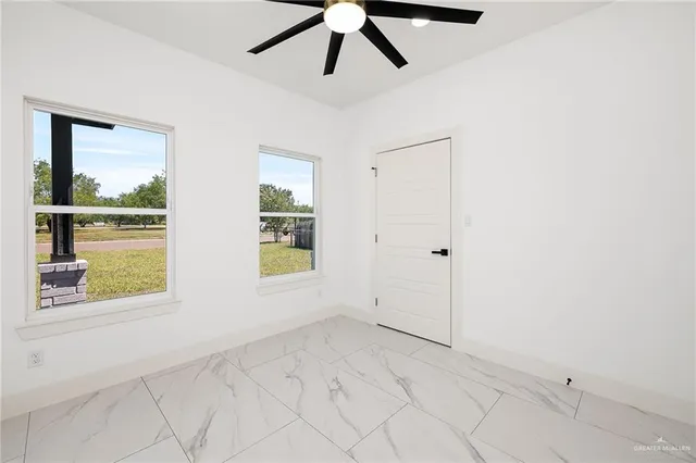 a view of empty room with window and ceiling fan