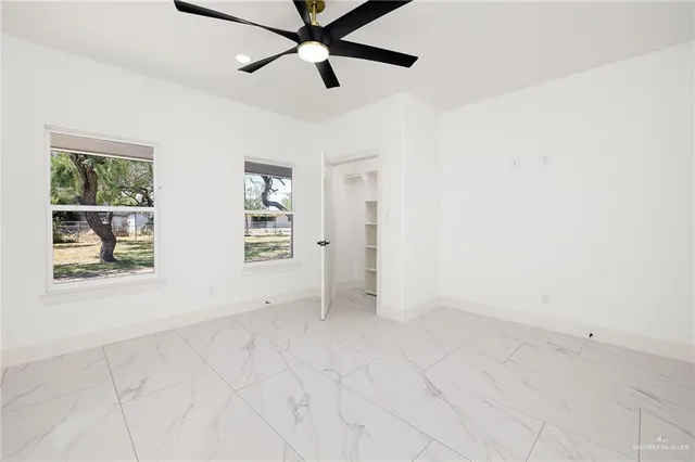 an empty room with windows and fan