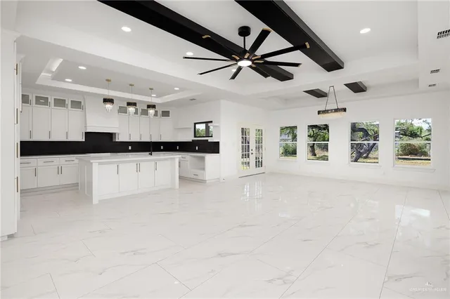 a large white kitchen with a large window and stainless steel appliances