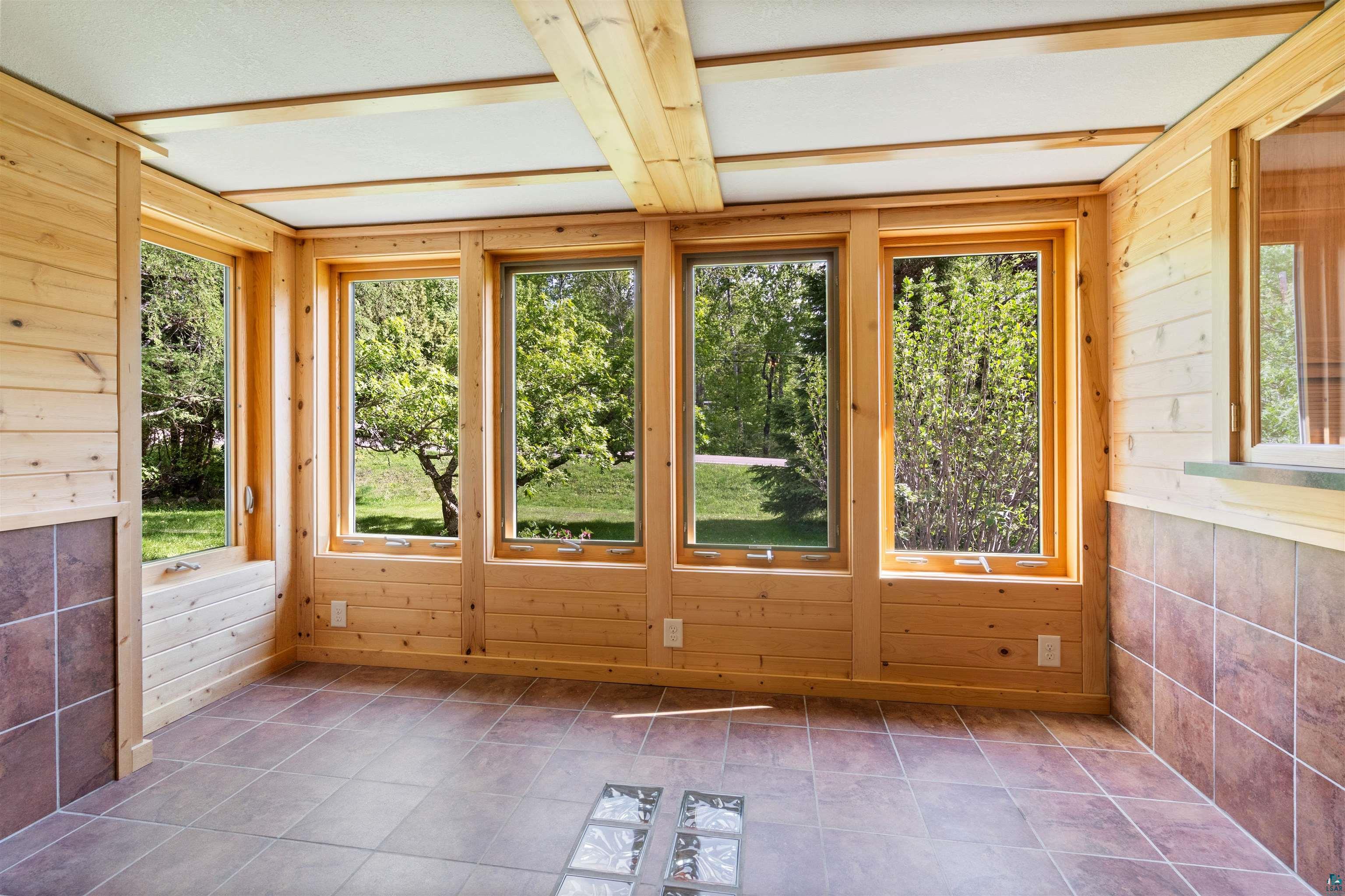 4793 Anderson Road Hermantown, MN 55811 - Photo 15 of 39 Wood-paneled room featuring multiple windows, exposed ceiling beams, and a tiled floor