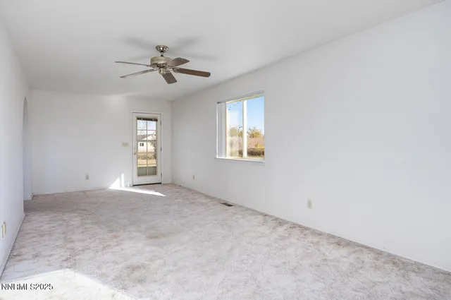 an empty room with windows and fan