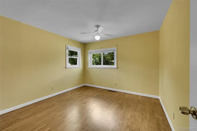 a view of empty room with wooden floor and fan