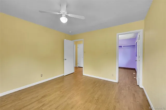 an empty room with wooden floor and fan