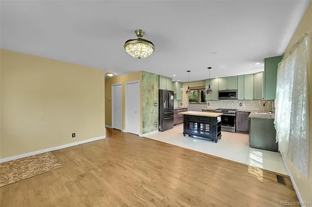 a living room with stainless steel appliances furniture a chandelier and a view of kitchen