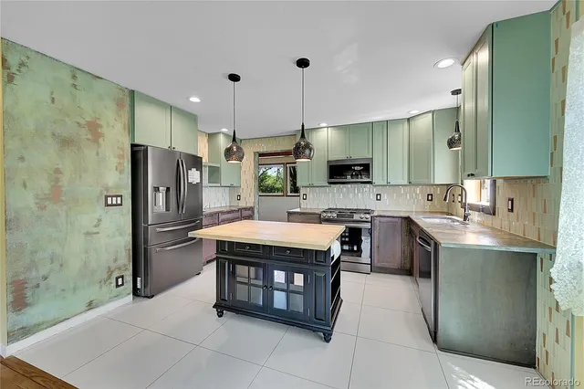 a kitchen with stainless steel appliances granite countertop a sink a stove a refrigerator and a refrigerator