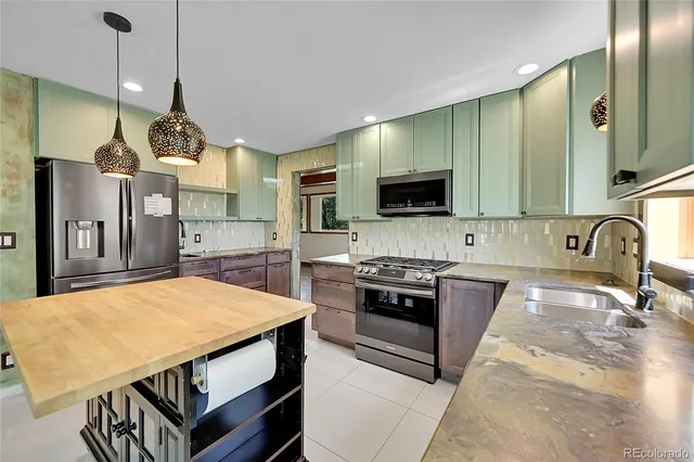 a kitchen with stainless steel appliances a stove a sink a oven a refrigerator a stove and white cabinets