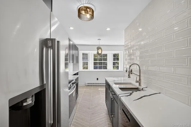 a kitchen with a sink stainless steel appliances a counter top space cabinets and a window