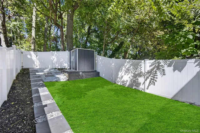 a view of a backyard with plants and large tree