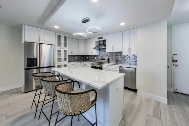 a kitchen with kitchen island granite countertop a sink a counter top space stainless steel appliances and cabinets