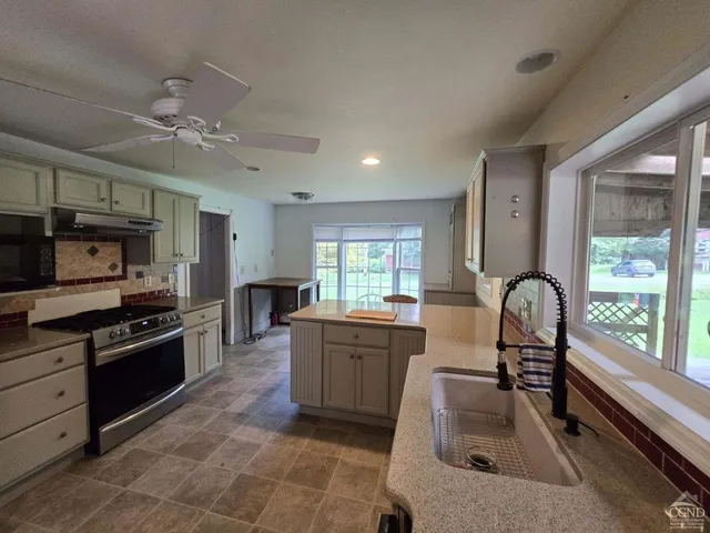 a large kitchen with granite countertop a stove top oven a sink a dining table and chairs