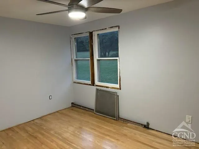 an empty room with a window and ceiling fan