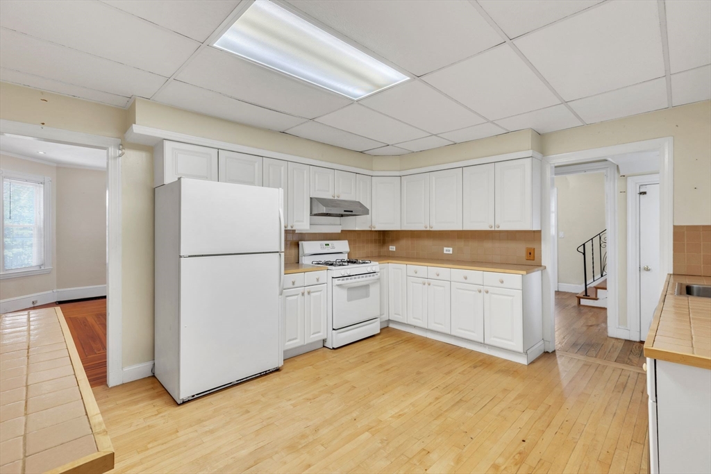49 Laurel Street Watertown, MA 02472 - Photo 15 of 42 a kitchen with a refrigerator a white cabinets and wooden floor