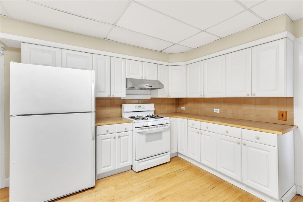 49 Laurel Street Watertown, MA 02472 - Photo 16 of 42 a kitchen with a sink a refrigerator and white cabinets