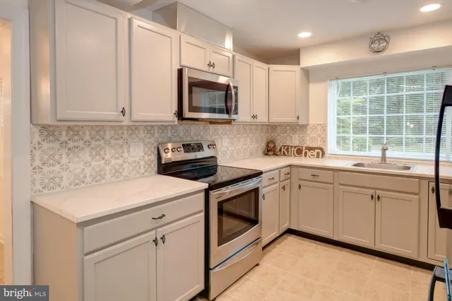 a kitchen with stainless steel appliances granite countertop white cabinets a sink and a oven
