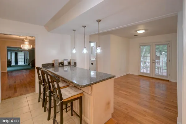 a kitchen with stainless steel appliances granite countertop a kitchen island a sink dishwasher a dining table and chairs with wooden floor