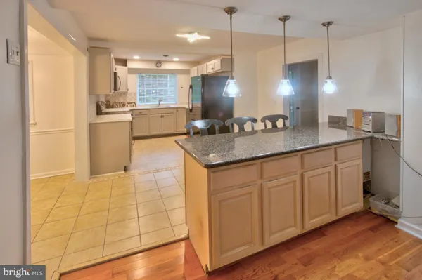 a kitchen with kitchen island granite countertop a sink a counter space appliances and cabinets