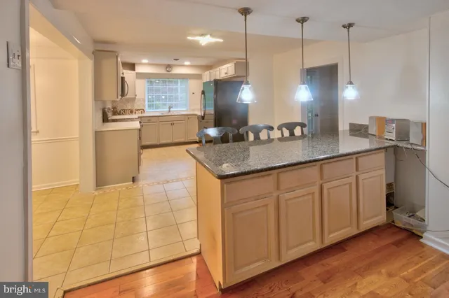 a kitchen with kitchen island granite countertop a sink a counter space appliances and cabinets