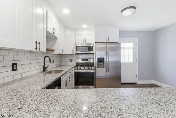 a kitchen with stainless steel appliances granite countertop a sink a stove a refrigerator and a oven