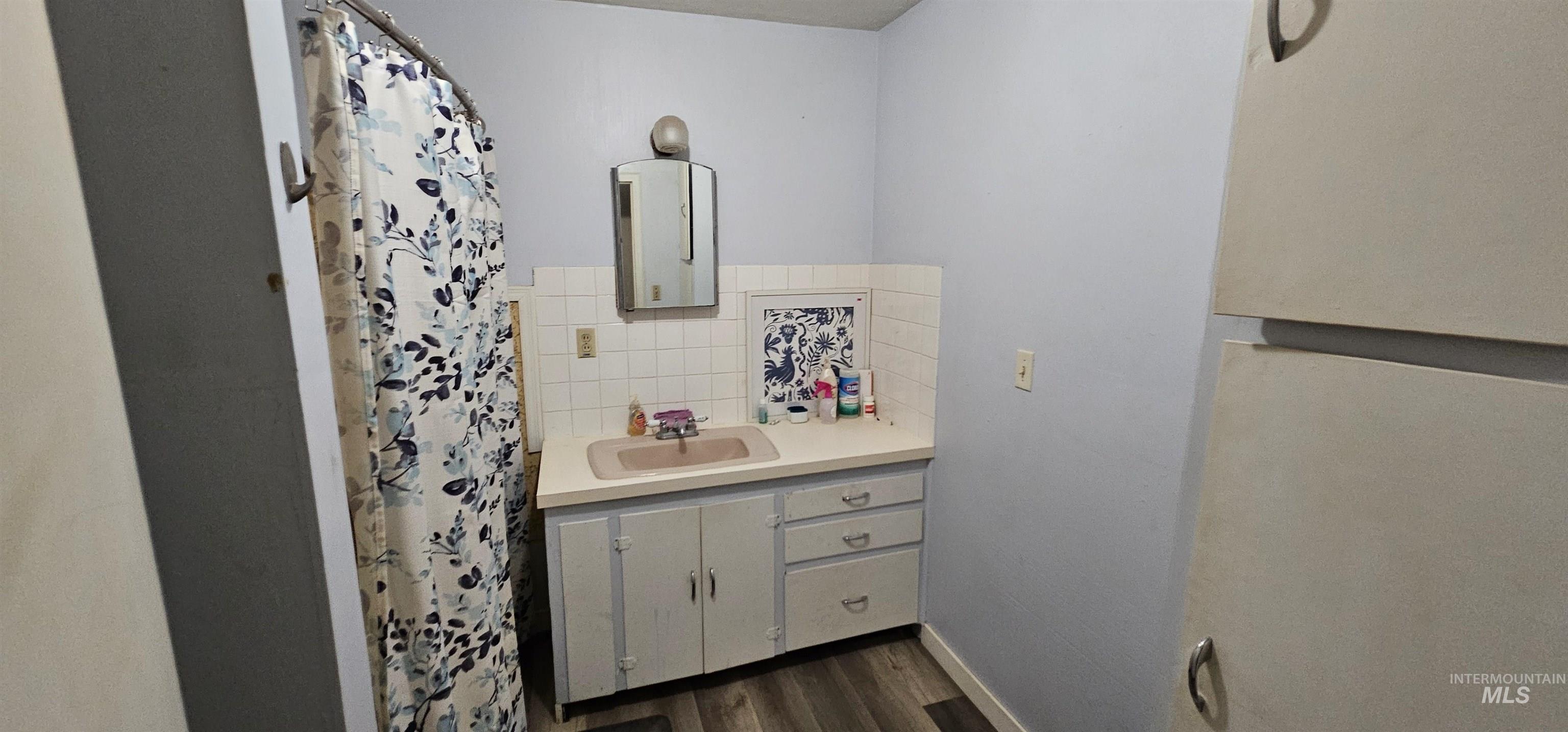 555 15th Street Vale, OR 97918 - Photo 17 of 27 Full bathroom with vanity, a shower with curtain, decorative backsplash, and dark wood-style floors