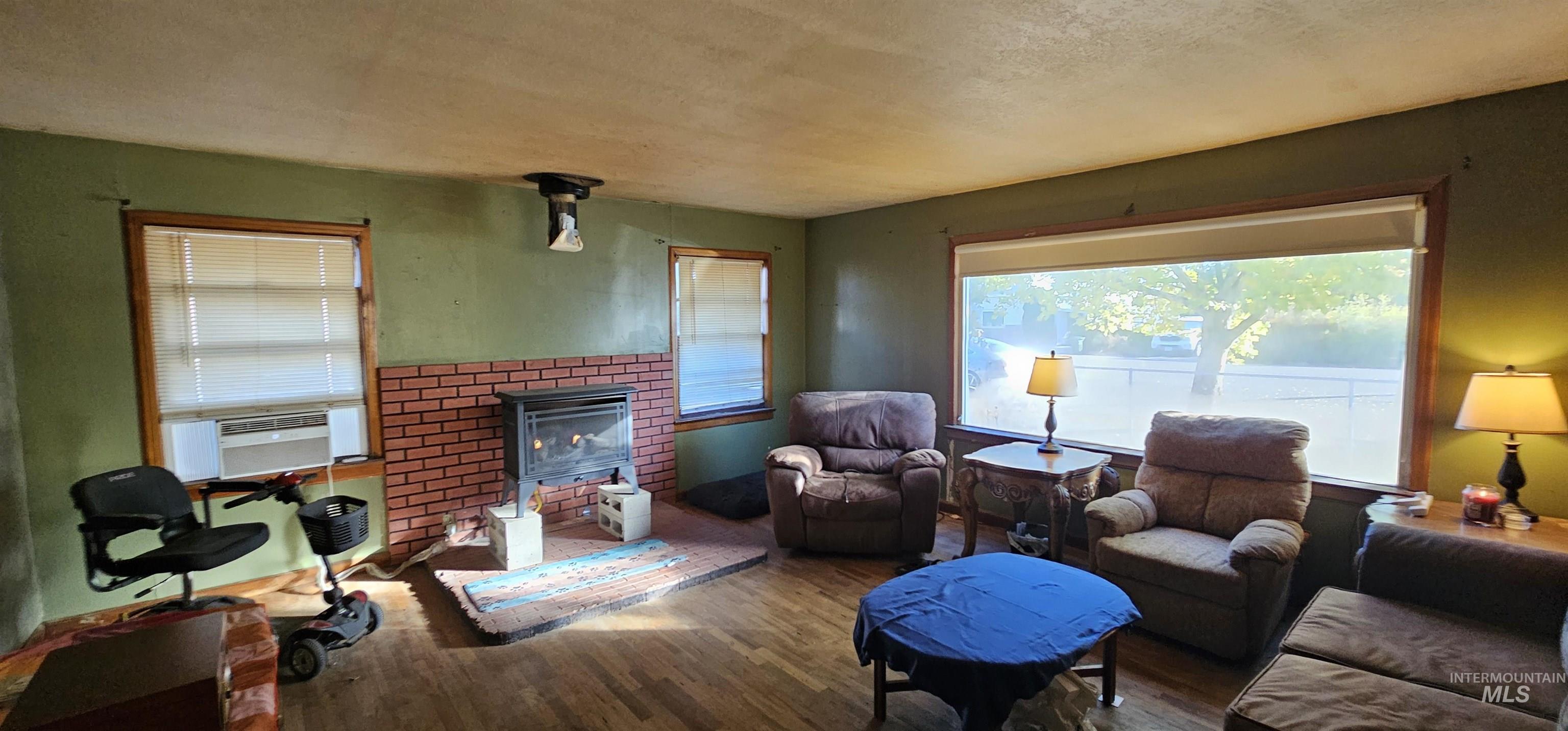 555 15th Street Vale, OR 97918 - Photo 5 of 27 Living area featuring wood finished floors, a fireplace, a textured ceiling, and cooling unit