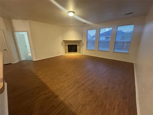 an empty room with windows and fireplace