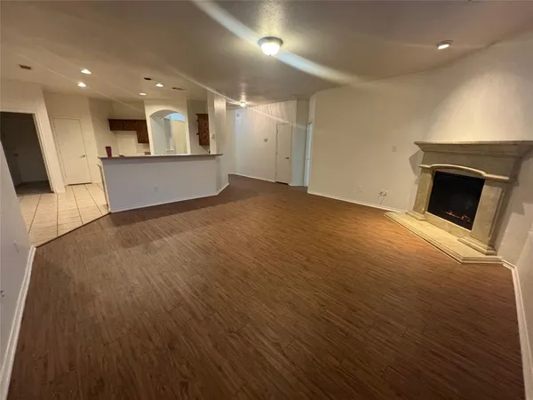an empty room with wooden floor and a kitchen